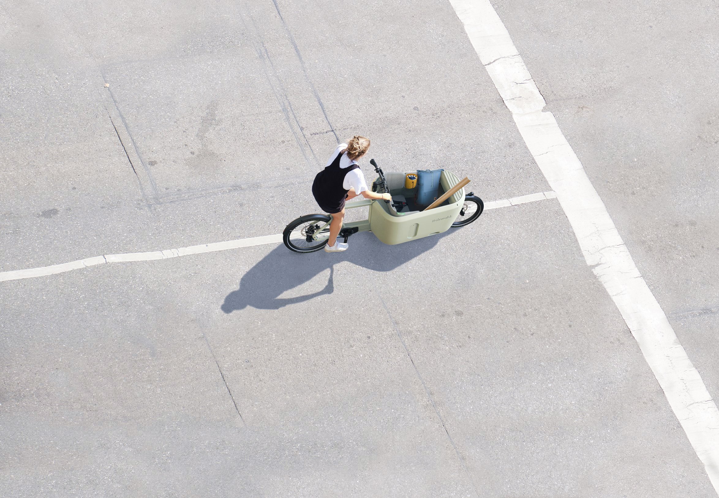 Person fährt mit einem Lastenfahrrad auf der Straße.